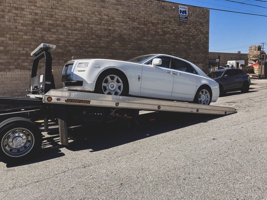 Rolls Royce getting towed and delivered to a transporting company taking the car over seas.