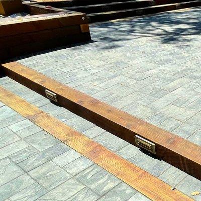 Timber inset beams to soften the expansive area of this beautiful interlock paver patio (plus: down lights mounted in wood beam steps).