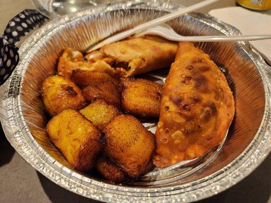 Two empanadas and a side of plantains fill this container.