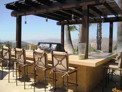 Outdoor kitchen, concrete counter top and bar seating with pergola