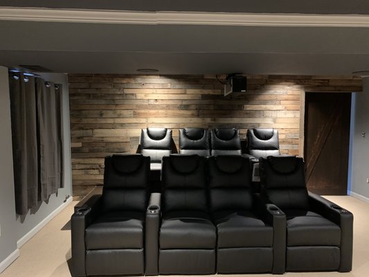 Reclaimed wood accent wall, stadium seating platform and comfortable leather theater chairs