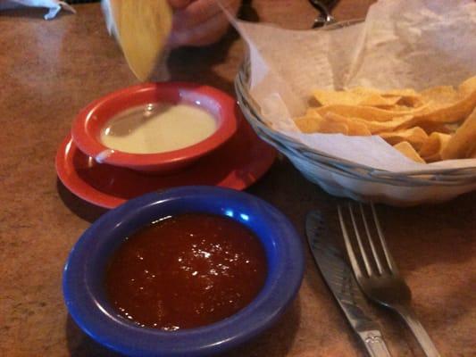 White cheese dip, chips, and salsa.