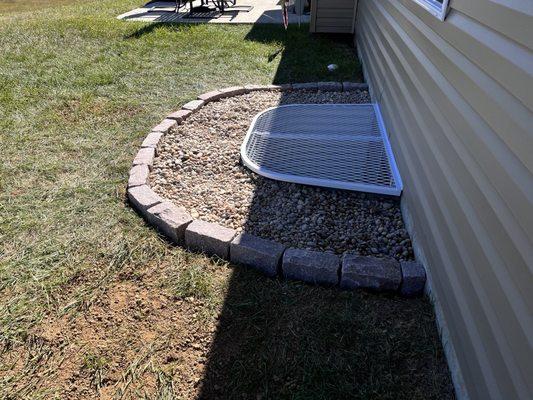 Installed rock garden around window well cover.