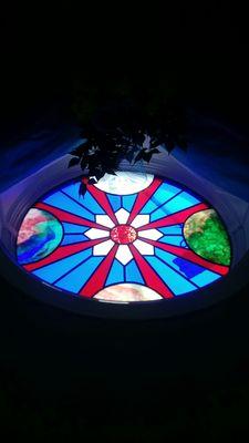 Stained glass window brings to mind the source and planets. We are all part of the great reality.