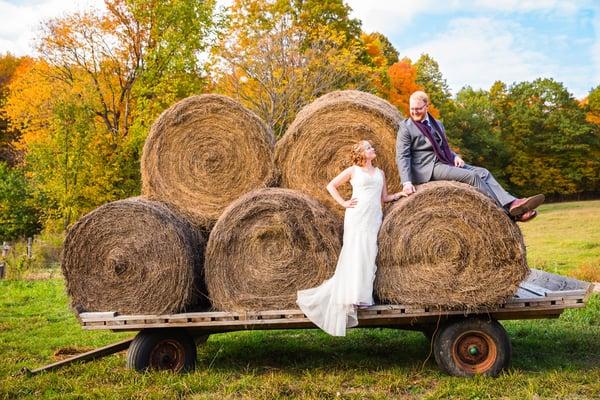 Fall Gatsby wedding with couple posing on giant hay bales