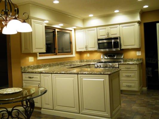 After. Glazed white cabinets, granite countertops, and new lighting make this kitchen a showcase.