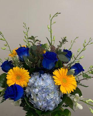 Blue Roses, Dendrobian Orchids, Hydrangeas, Gerber Daisies, and Mixed Greens in a Glass Vase