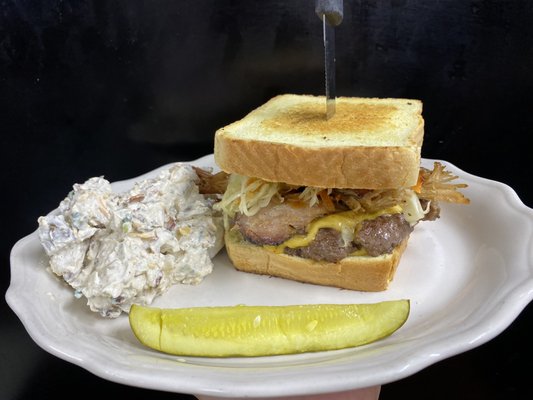 Burger topped with brisket Carolina slaw on texas toast with served with a pickle and side of loaded baked potato salad