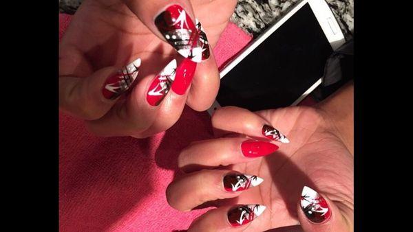 Red Nails with black ,white designs she likes them with a point nice and sharp . Make a appointment today why wait