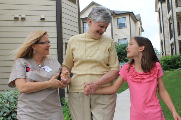 Caring Senior Service caregiver going on a walk with a client and her family