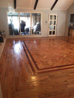 This custom installation features a Red oak herringbone inlay with a double Brazilian Cherry border