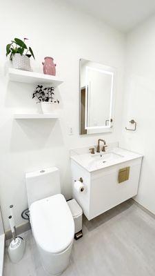 Bathroom with floating vanity and backlit recessed mirror and floating shelves