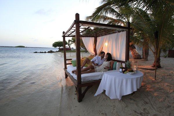 Couple enjoying a beach cabana at sunset.