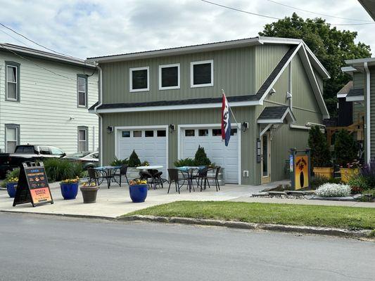 Front of building. Outdoor seating. Entrance on right, next to sign.