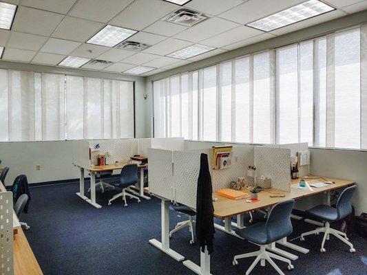 Bright and beautiful Dedicated Desk room featuring individual workstations and sit/stand desks.