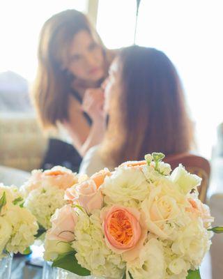 Close-up of bridal bouquet with blurred makeup artist and bride in background, captured in Sacramento by Cherish the Moment Photography