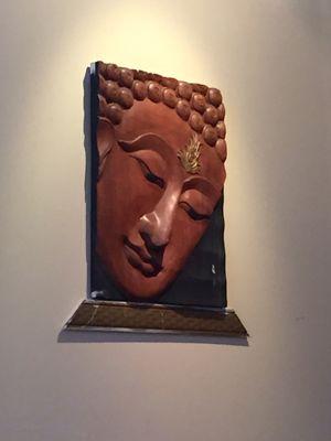 Wooden curved Buddha hanging on the wall