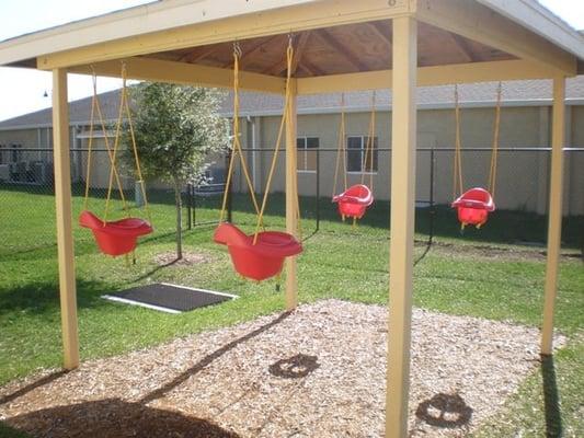 Infants and Toddlers relax and enjoy swinging on the playground.