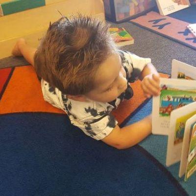 Little boy on carpet looking through a picture book.