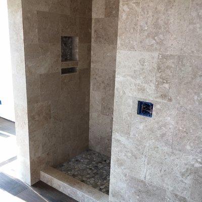 Beautiful stone shower with river rock mosaic.