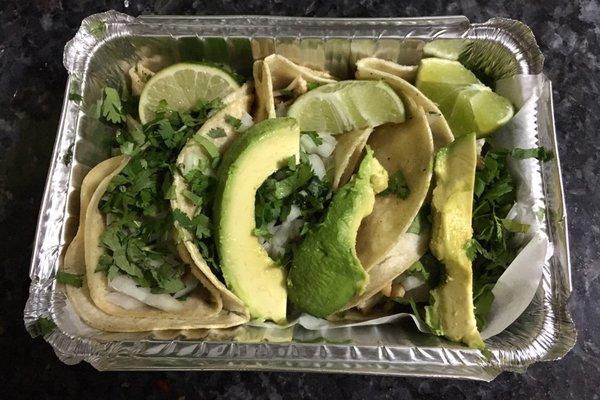 Chicken tacos to go. Grilled chicken with fresh cilantro and chopped onion topped with avocado and lime slices