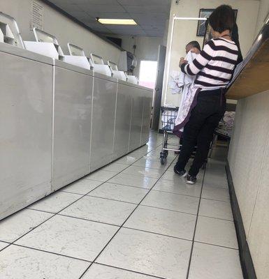 Owner helping an older lady fold a comforter and then finish off her clothes.