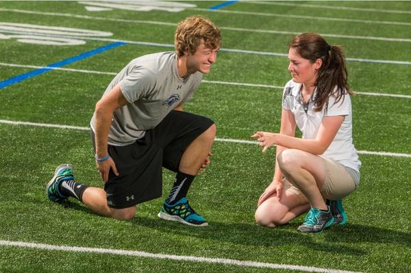 Pivot athletic trainer Katie Cicia working with a student athlete to determine what area of his leg is causing the most pain.