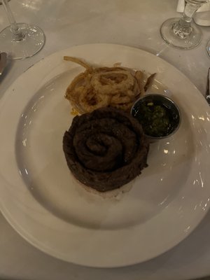 Skirt steak served with onion rings and chimichurra sauce