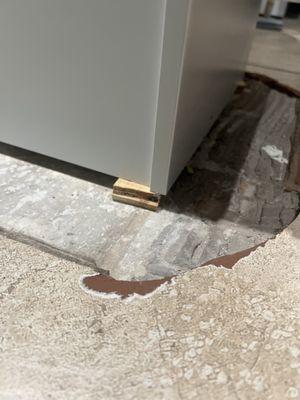 Broken tile with wooden chip to level out the cabinet