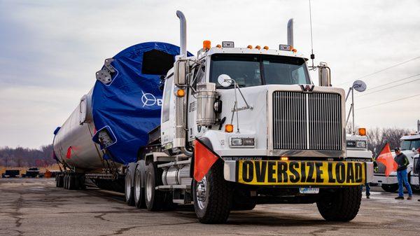 Windmill tower sections on stretch trailers.