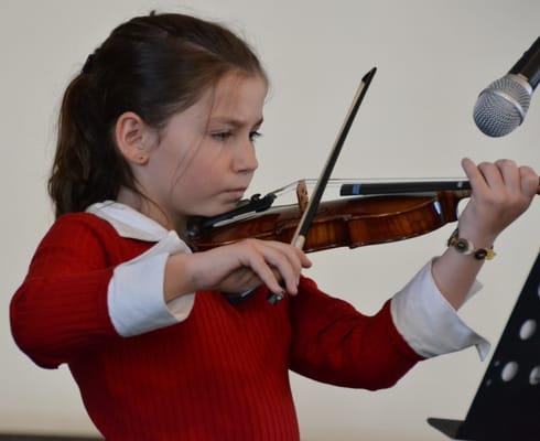 Violin student performing at our recital. Violin lessons ages 4 through adult!