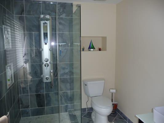 blue marble tiles with glass shower enclosure; also installed new toilet and recess shelf behind the toilet