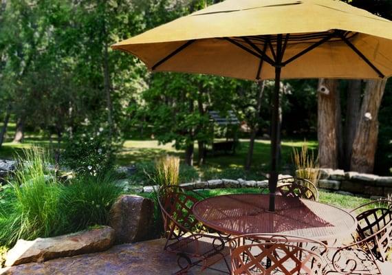 This patio was extended to provide an outdoor dining area with views of the surrounding woods.  A sandstone wall retains the colorful beds.