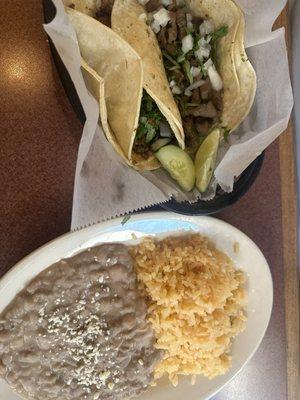 Two tacos and a side of rice and beans