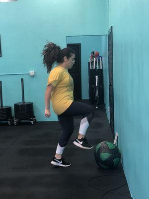 Cynthia performing med ball taps during a group fitness HIIT class.