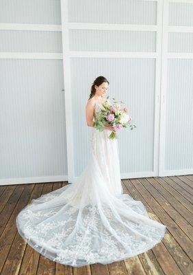 Bride standing alone with flowers looking down at them.