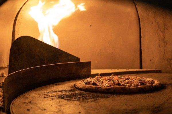 Pizza being heated in a REAL wood-fired pizza on the wood-deck of two twisting rivers