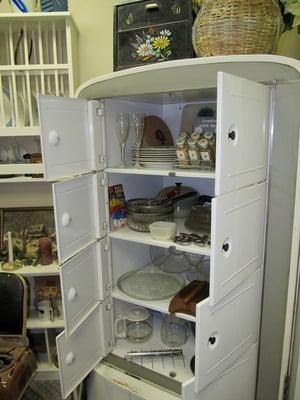 Old, working refrigerator filled with antique kitchenware