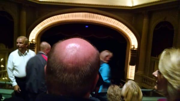 The stage is behind this man's head.  I am seated directly behind him. I paid money for this?