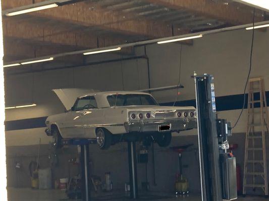 An old classic car on a lift.