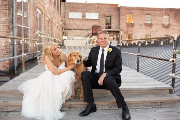 Couole snuggles with dog on an outdoor deck in an industrial chic setting. Photo by Ciao Bella Studios