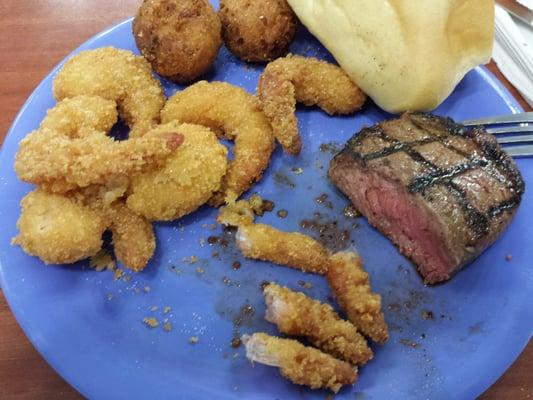 First plate, medium rare steak with fried shrimp,  yeast roll,  and hushpuppies.