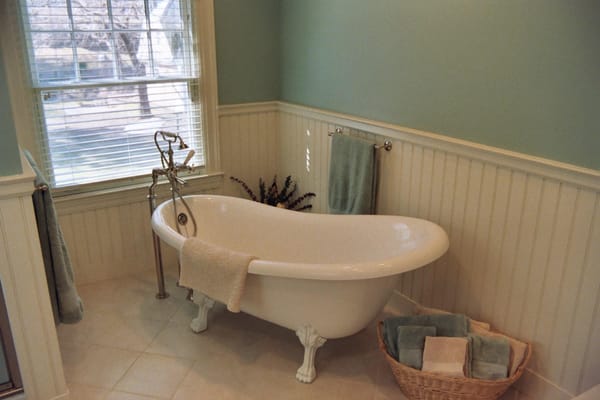 The separate tub/shower and toilet area of this remodeled bath continues the wainscoting seen in the vanity picture...