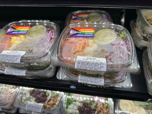 Salad options with a sticker noting that a portion of the purchase benefits local LGBTQ+ charities.