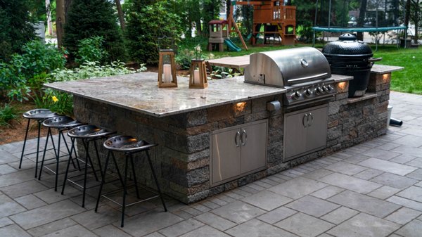 Outdoor kitchen with bar seating and built-in barbecue.