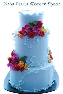 Blue Belle Wedding Cake - Vibrant wild roses and ranunculus with soft blue ribbons; a festive cake for a festive occasion.