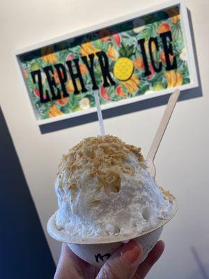 Macadamia nut ice cream topped with shaved ice covered in coconut syrup and toasted coconut