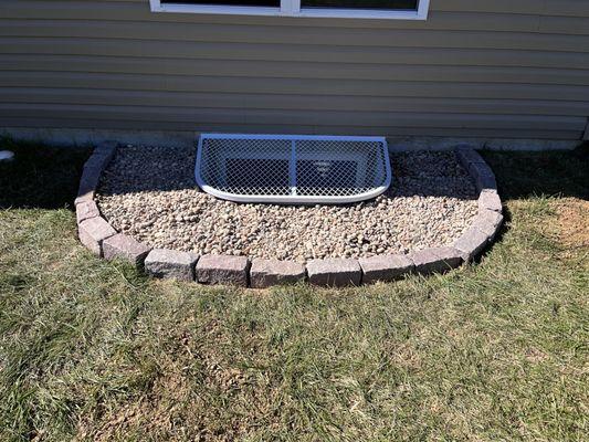 Installed rock garden around window well cover.