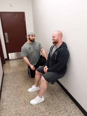 Trainers demonstrating a Wall Sit for our Instagram posts