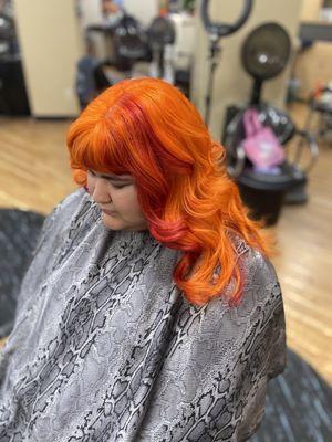 Vibrant fashion color orange with a red panel, long layered haircut and soft curl style